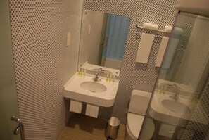 A bathroom with a white sink, a mirror, a toilet, and a shower area. - OCT East Cargo Hostel Shenzhen (Shenzhen)