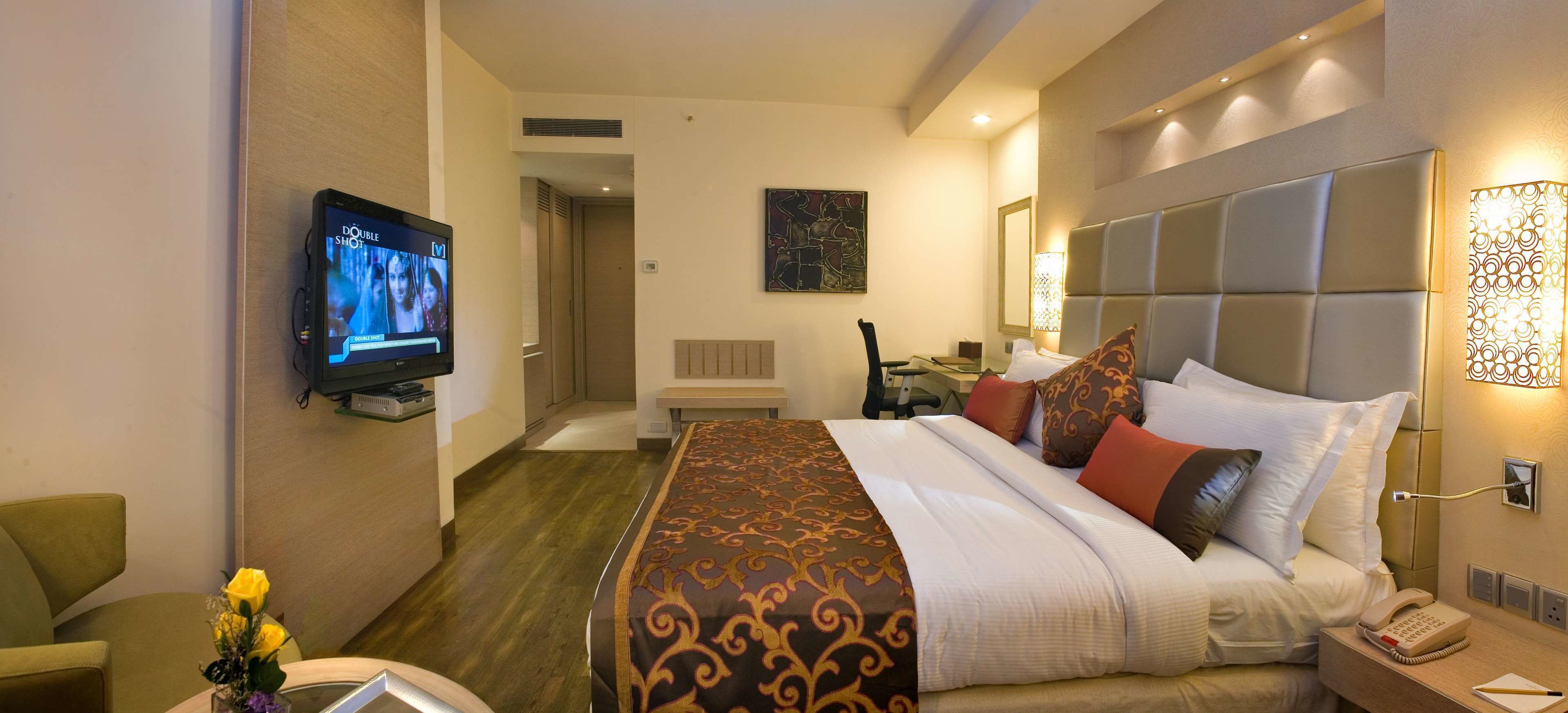 Ein Hotelzimmer mit Bett, Fernseher, Schreibtisch und Stuhl.