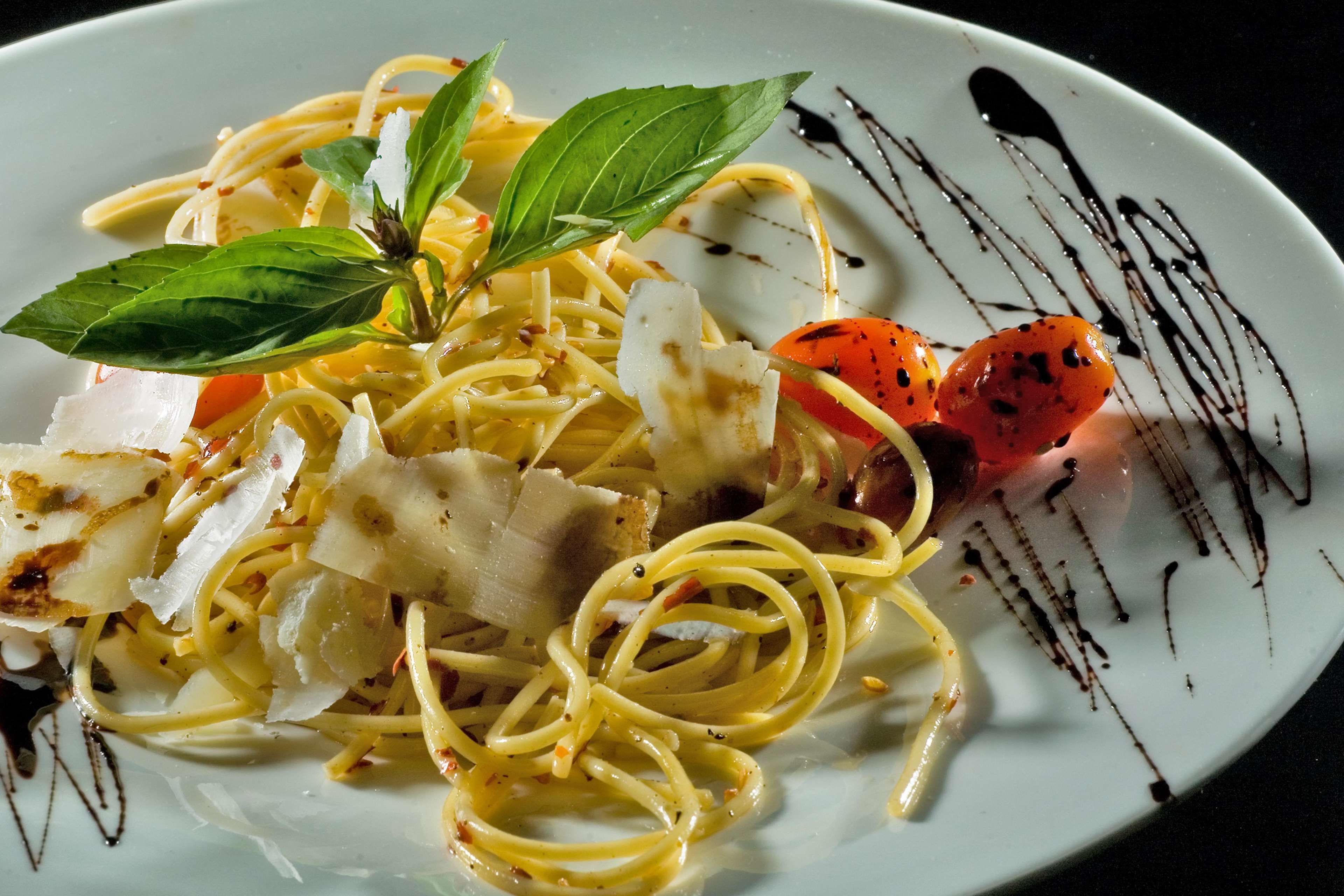 A plate of spaghetti with tomato and basil garnish.