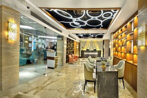 A modern interior with a marble floor, a reception desk, and a seating area with chairs and a table. - The Sonnet (Bidhannagar)