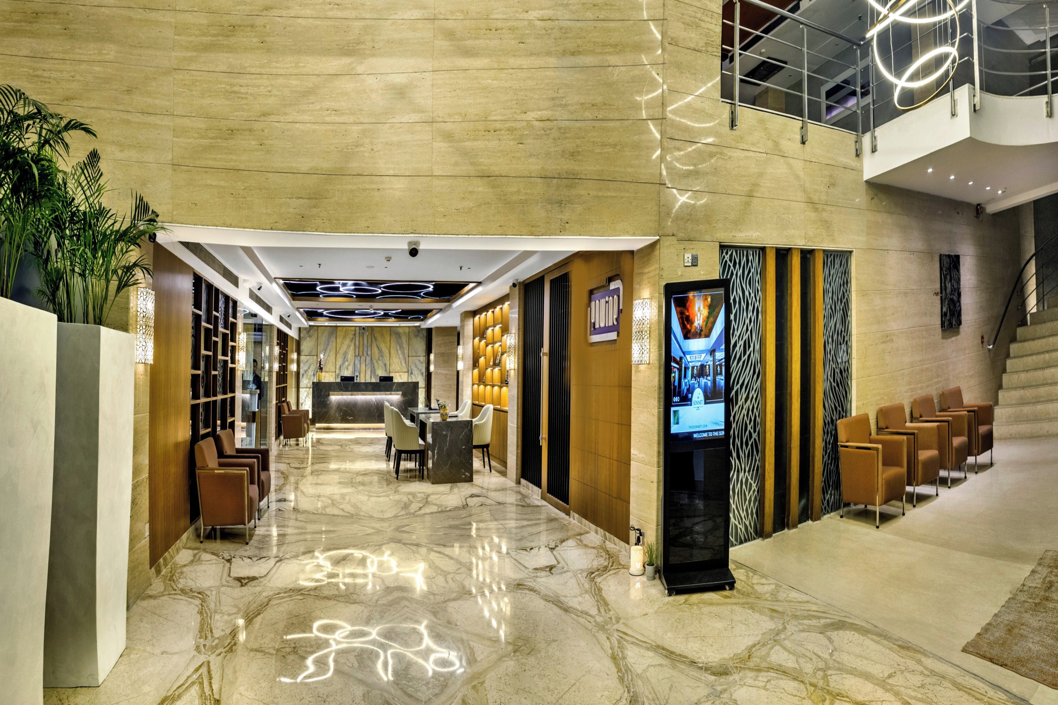 A hotel lobby with a reception desk, seating area, and a staircase.