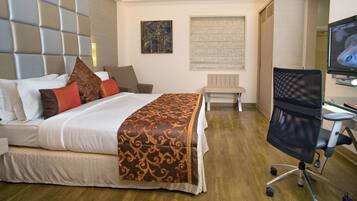 A hotel room with a bed, a desk, a chair, and a television.
