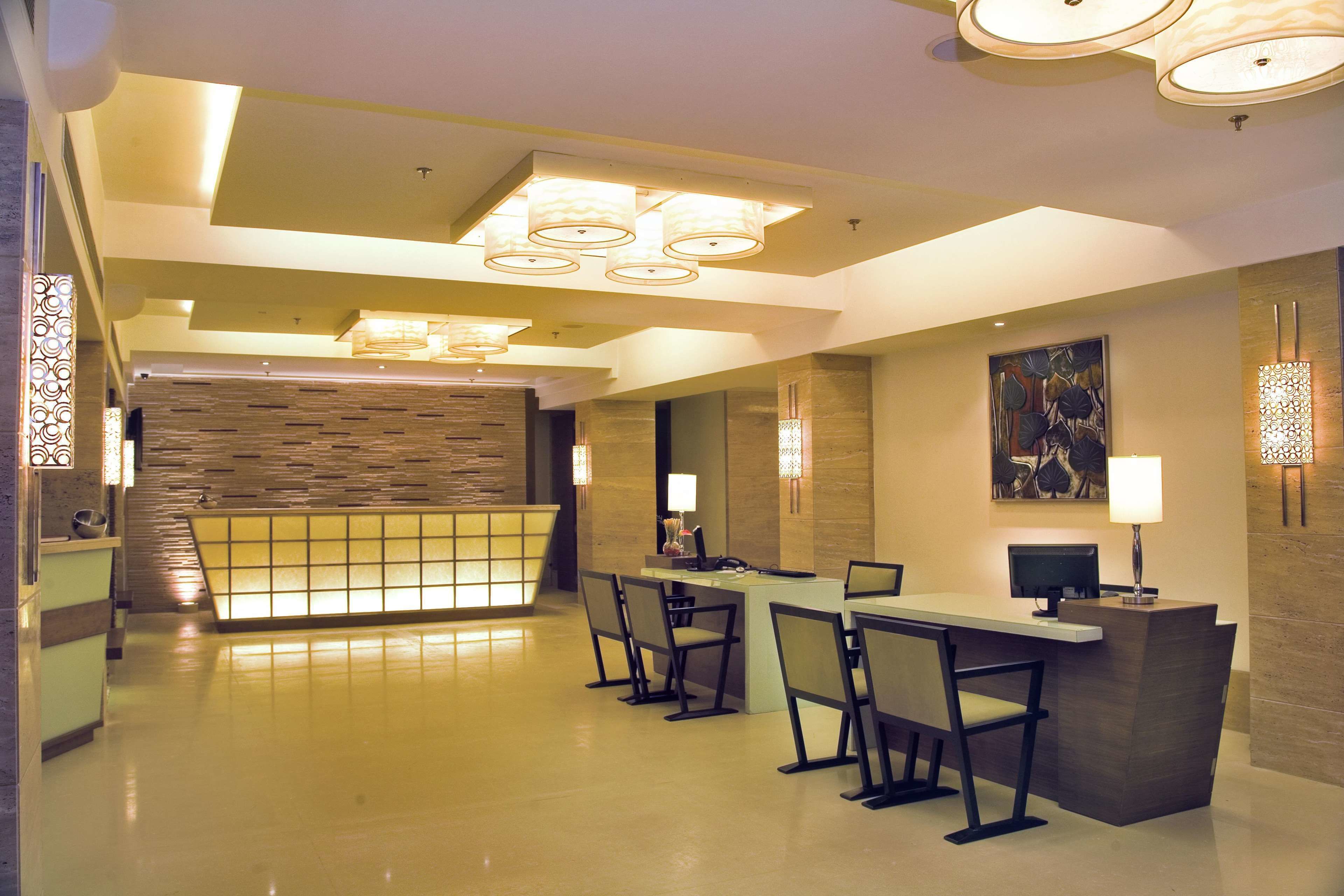 A hotel lobby with a reception desk, seating area, and a decorative wall.