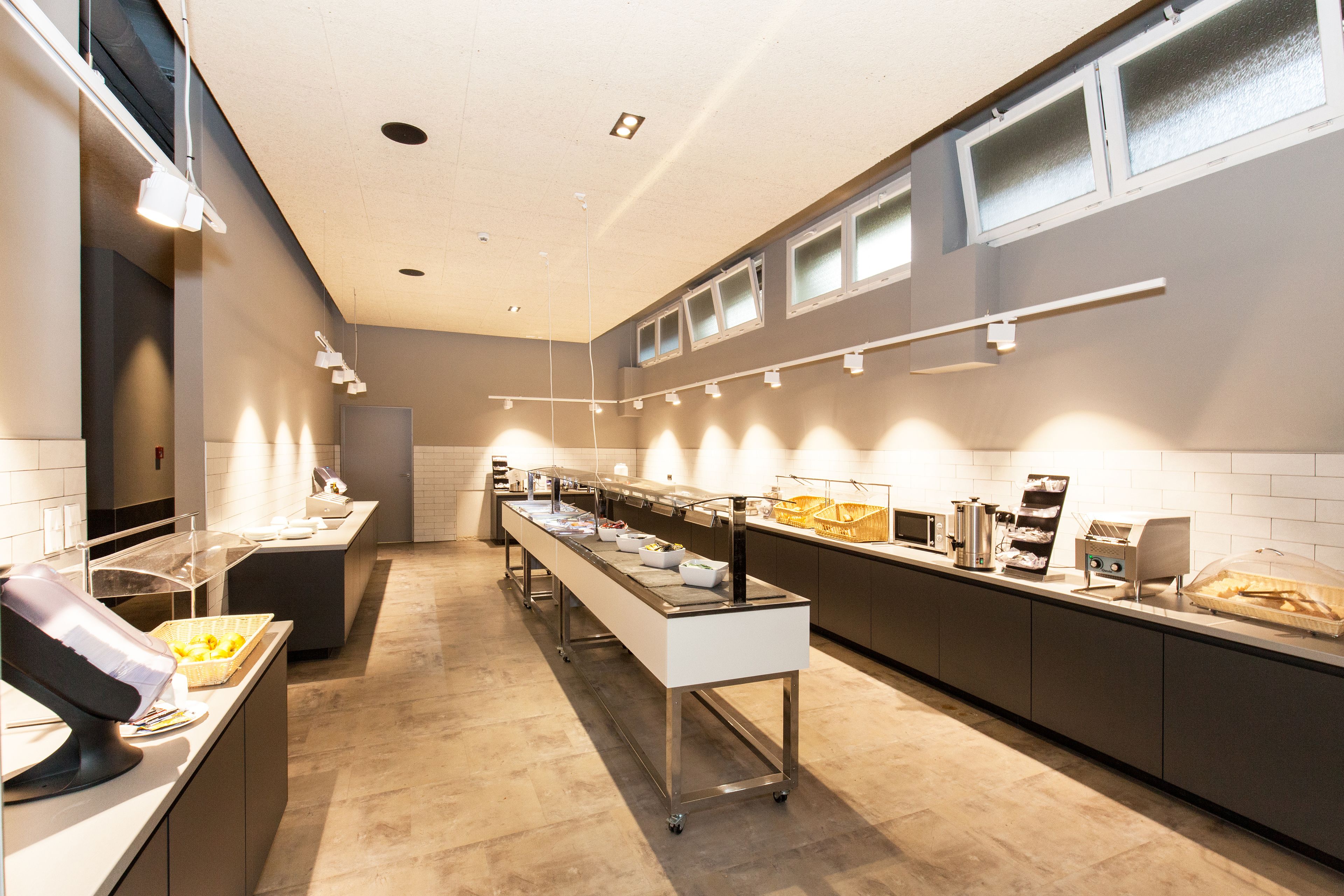 A modern kitchen with a long counter, various appliances, and a clear glass display case.