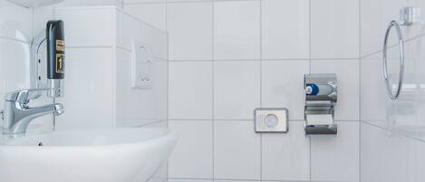 A modern bathroom with a white sink, toilet, and bidet.