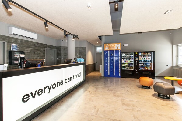 A reception area with a counter, vending machines, and seating. - a&o Nürnberg Hauptbahnhof - Hostel (Nuremberg)