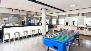 Un bar moderno con mesa de fútbol, taburetes y mostrador con exhibición de bebidas.
