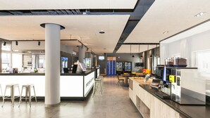 Un área de bar moderna con mostrador, taburetes y una máquina de café.