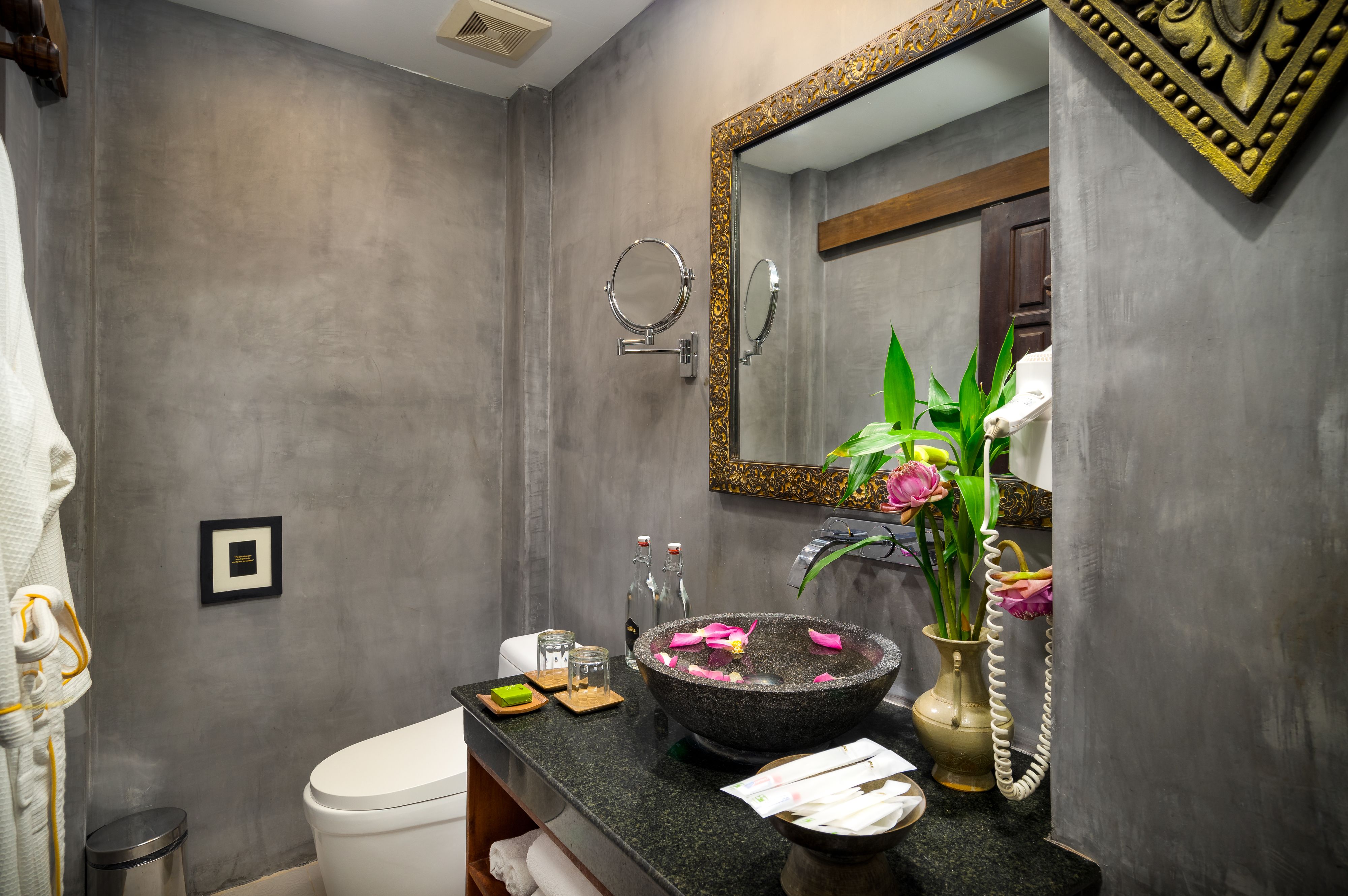 A modern bathroom with a large mirror, a round sink, and a toilet.