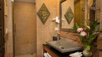 Une salle de bain avec un lavabo en granit, un miroir, une douche et des carreaux décoratifs.
