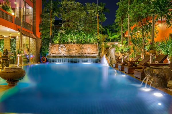 Una piscina techada, una piscina al aire libre, sombrillas