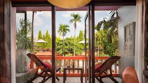 A balcony with two wooden chairs, a small table, and a decorative bowl.