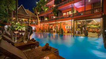 A hotel with a large outdoor pool, multiple balconies, and tropical decor.