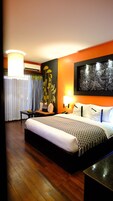 Habitación de hotel con una cama grande, una mesita de noche, una lámpara, aire acondicionado y una pared con diseño floral.
