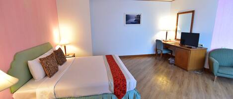 Una habitación de hotel con cama, escritorio, silla y televisor.