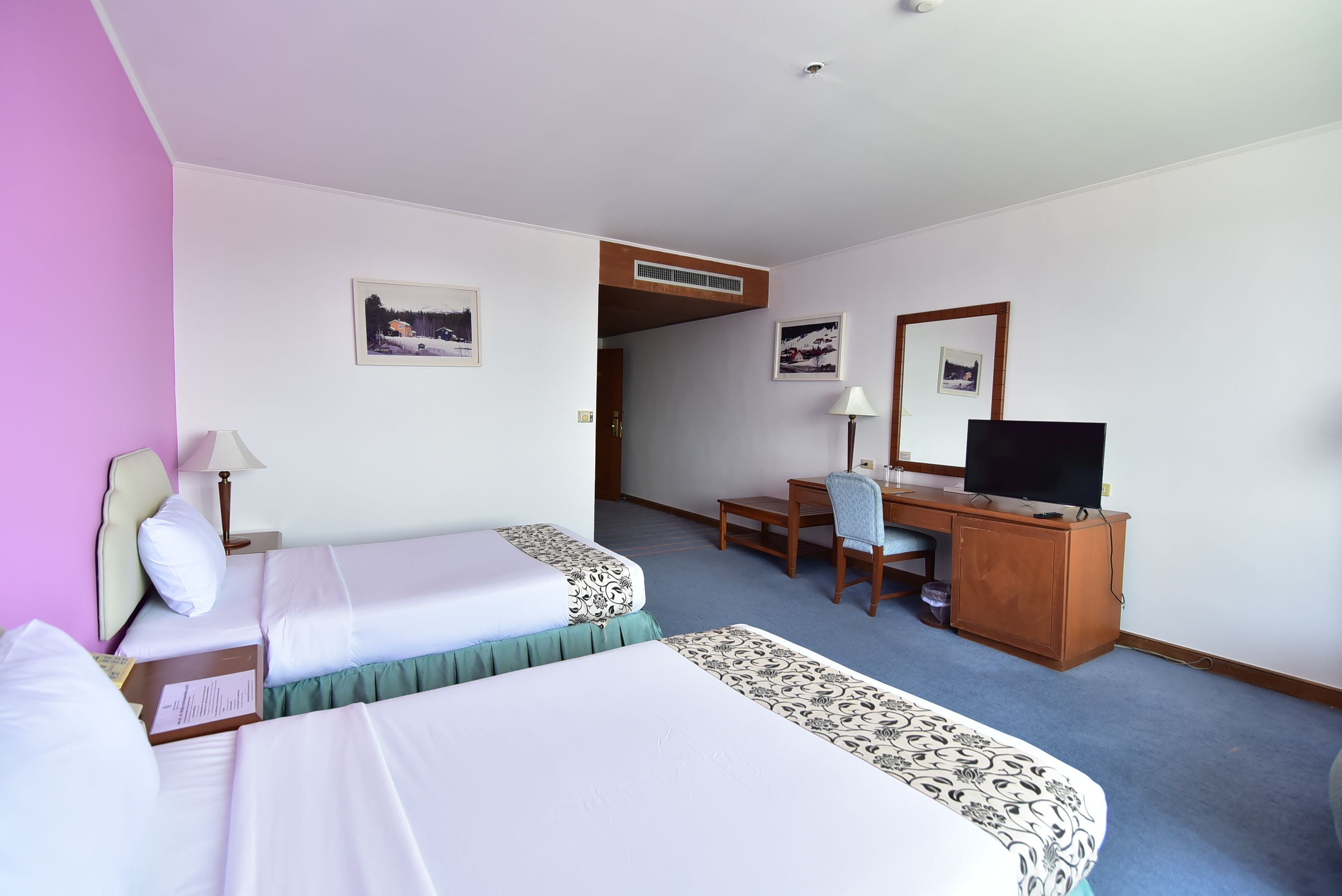 Habitación de hotel con dos camas, un escritorio, una silla, un televisor y una ventana.