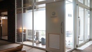 A smoking room with a glass door, a brick wall, and a view of the outside balcony. - Imari Grand Hotel (Imari)