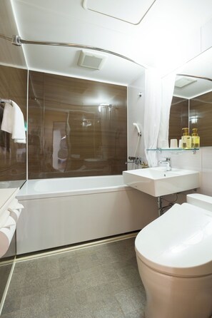 A modern bathroom with a bathtub, a toilet, a sink, and a glass shower enclosure. - Imari Grand Hotel (Imari)