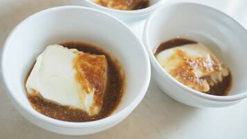 Three white bowls containing a dessert with caramelized top and a brown sauce.