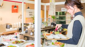 A buffet setup with various food items and a person serving food. - Imari Grand Hotel (Imari)