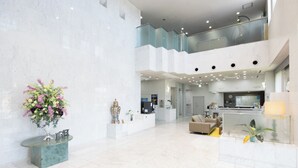 A spacious lobby with a reception desk, seating area, and a decorative vase with flowers. - Imari Grand Hotel (Imari)