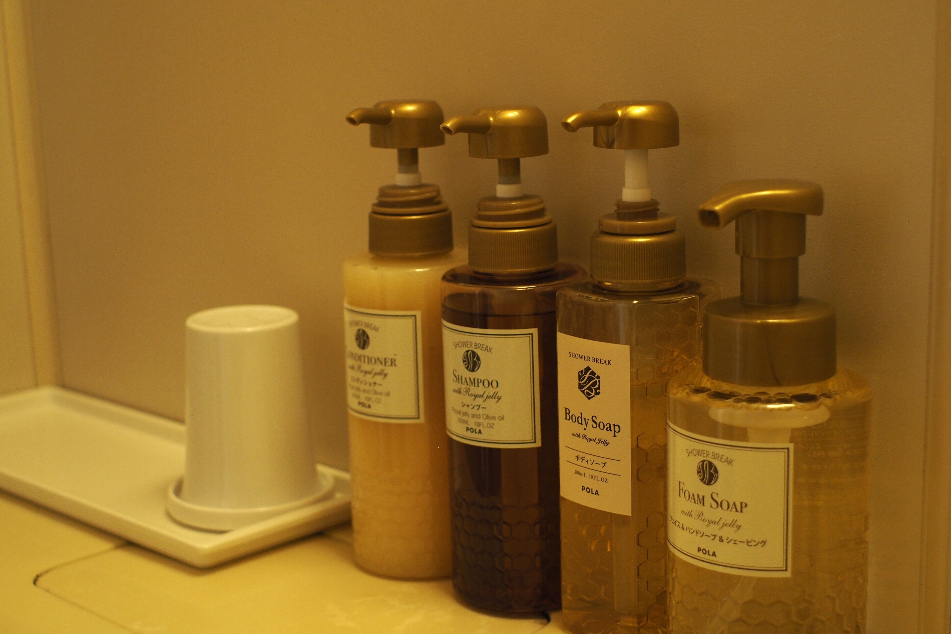 A bathroom with four bottles of body care products, including shampoo and body soap, arranged on a counter.
