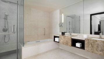 A modern bathroom with a glass-enclosed shower, a bathtub, and a vanity with two sinks and a mirror.