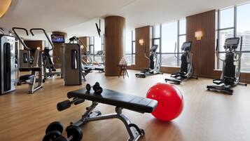 Ein modernes Fitnessstudio mit verschiedenen Trainingsgeräten, einer Bank, Hanteln und einem roten Trainingsball.