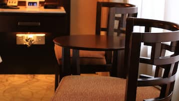 Habitación de hotel con una mesa de comedor, dos sillas, un televisor y una lámpara.