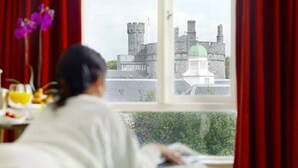 Ein Zimmer mit großem Fenster und Blick auf ein historisches Gebäude mit Türmen und einer grünen Kuppel.