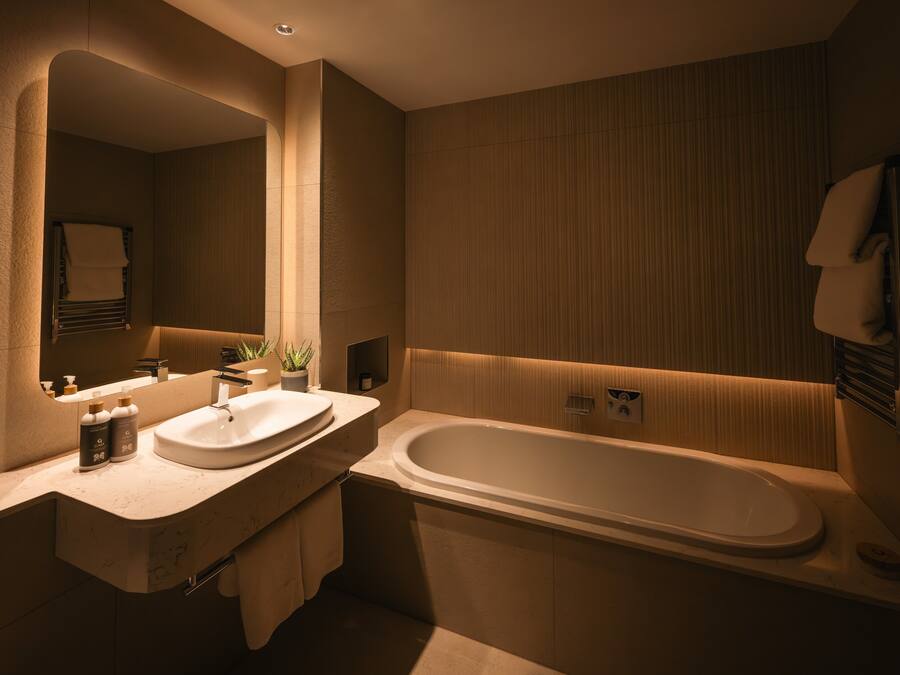 A modern bathroom with a large bathtub, a double sink vanity, and a mirror.