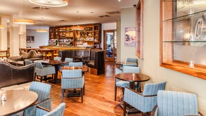 Eine Bar mit einer Holztresore, verschiedenen Sitzmöglichkeiten wie Sofas und Stühlen sowie einer Auswahl an Flaschen in Regalen.