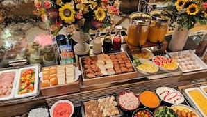 Een buffet met diverse soorten eten, waaronder vlees, groenten en desserts.