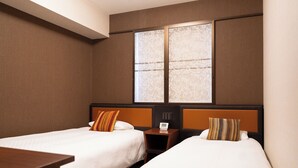 Een hotelkamer met twee eenpersoonsbedden, een nachtkastje met een klok en een raam met uitzicht.