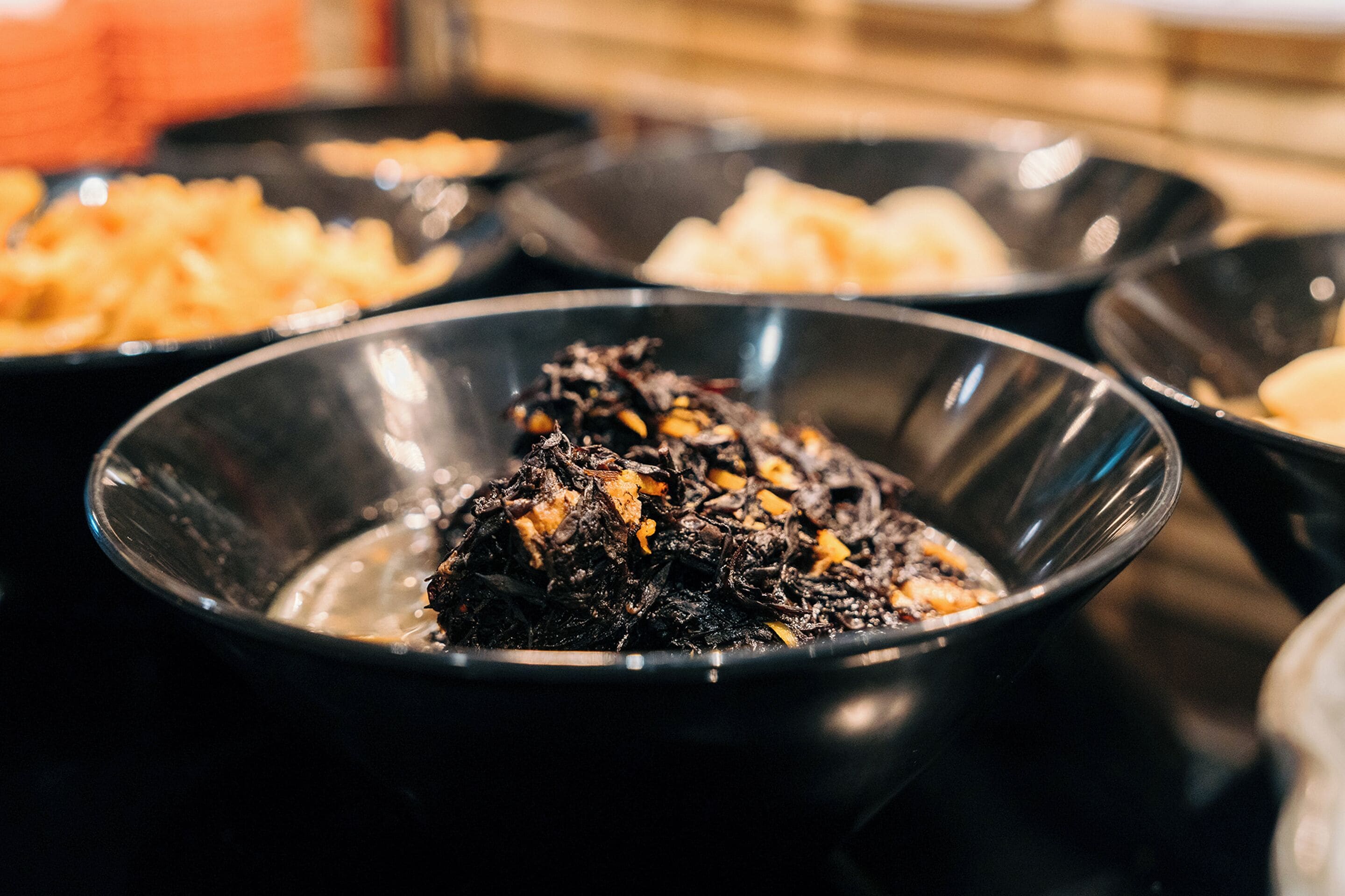A buffet with various dishes, including a bowl of dark-colored food with visible chunks.