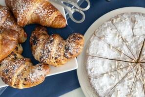 A variety of pastries including croissants and a pie on a plate, with a pair of scissors nearby. - Stella Marina (Ustica)
