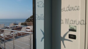 Un balcon avec des chaises longues, une balustrade et une vue sur la mer.