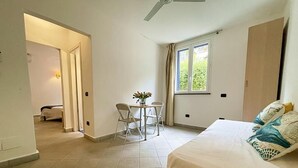 Une chambre à coucher comprenant un lit, un bureau avec une chaise, une fenêtre et une porte donnant sur une autre pièce.