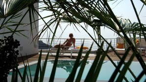 Un espace aménagé au bord de la piscine, avec des chaises longues et une vue sur l’océan.