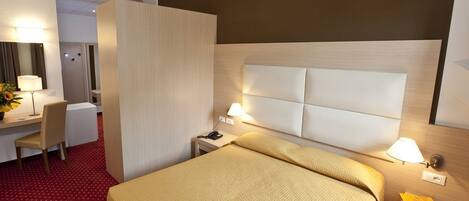 Une chambre d’hôtel comprenant un lit, des tables de chevet, un bureau et une chaise.