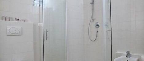 Un baño moderno con ducha envuelta en vidrio, inodoro blanco y lavamanos.