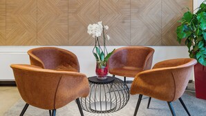 Una habitación con pared estampada, una mesa redonda y cuatro sillas marrones.
