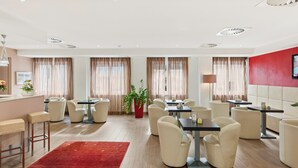 Un comedor de hotel con mesas, sillas, un tapete rojo y una planta en maceta.
