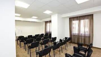 A conference room with rows of black chairs, a whiteboard, and a large window with curtains.