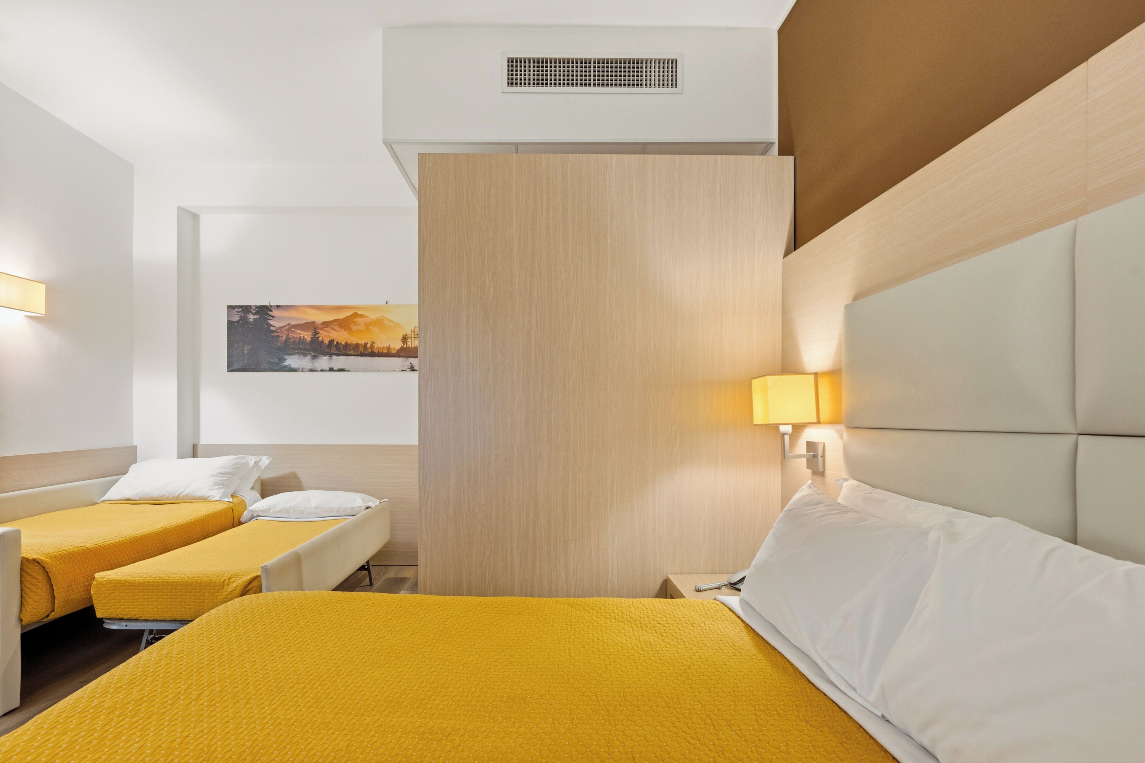 Une chambre d’hôtel avec deux lits, un tableau au mur et un luminaire.