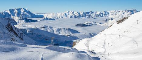 Paisaje montañoso cubierto de nieve con pistas de esquí y cielo despejado.