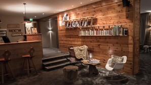 Een gezellig interieur met houten lambrisering, een bar, boekenkasten en comfortabele zithoeken.