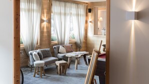 Een gezellige kamer met houten inrichting, een bank, een salontafel en een schilderij op een lessenaar.
