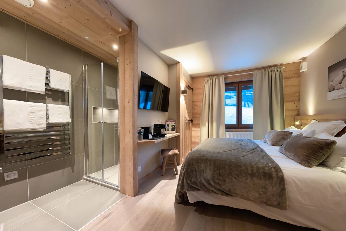 Une chambre moderne avec un grand lit, une télévision, une douche en verre et un plancher en bois.