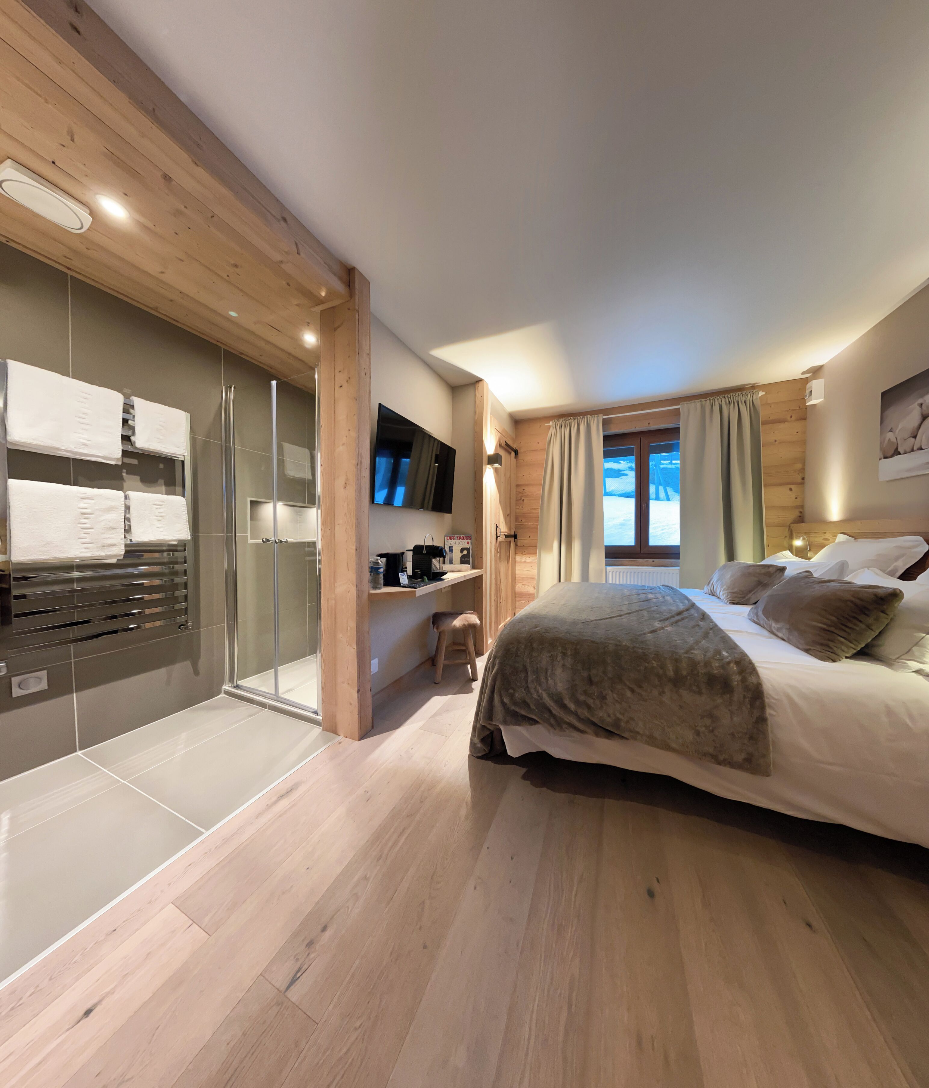 Une chambre à coucher comprenant un lit, une télévision, un bureau et une porte-fenêtre coulissante donnant sur une salle de bain.